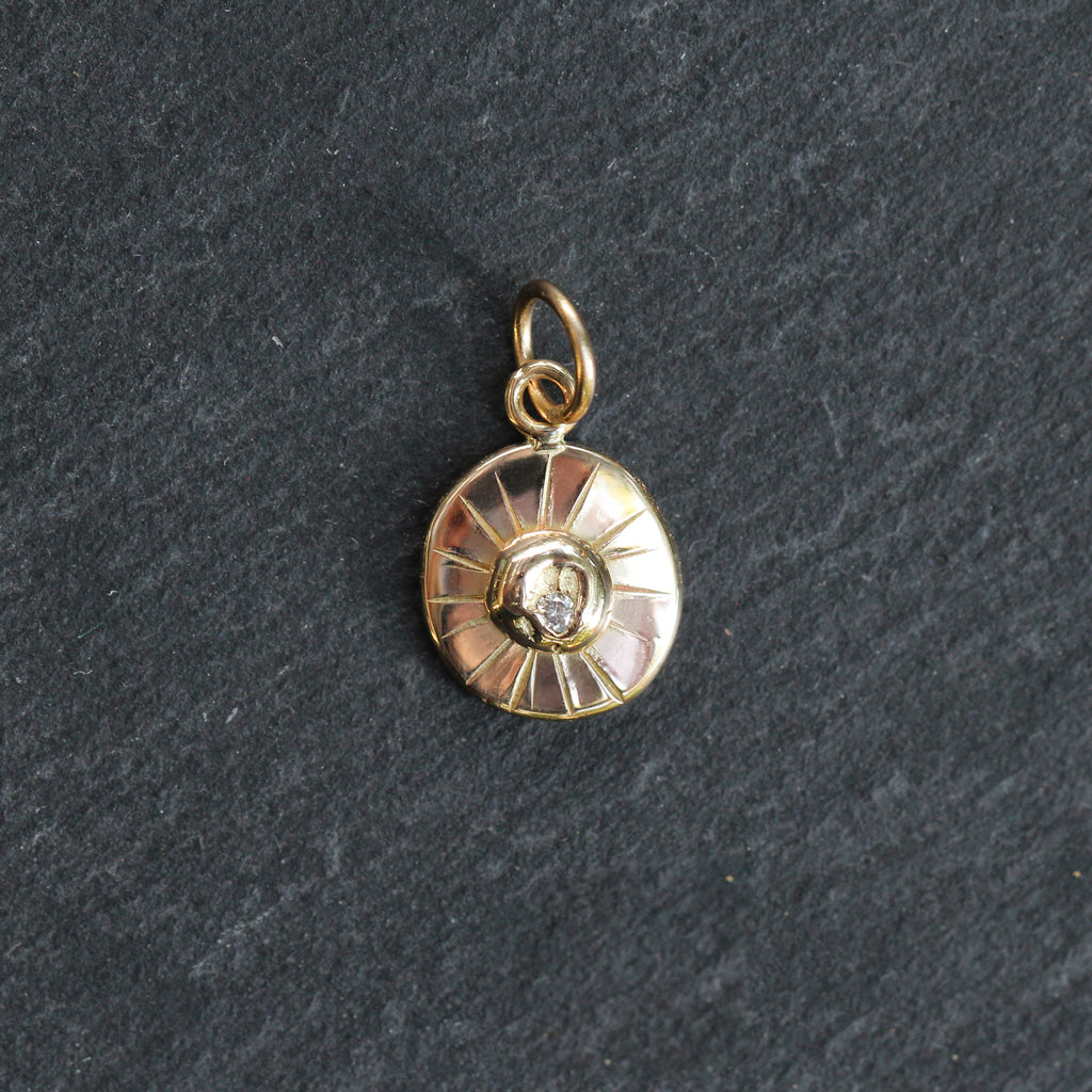 Gold pendant with a central gemstone on a dark gray background