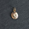 Gold pendant with a central gemstone on a dark gray background
