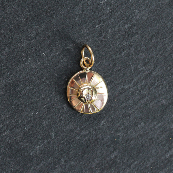 Gold pendant with a central gemstone on a dark gray background